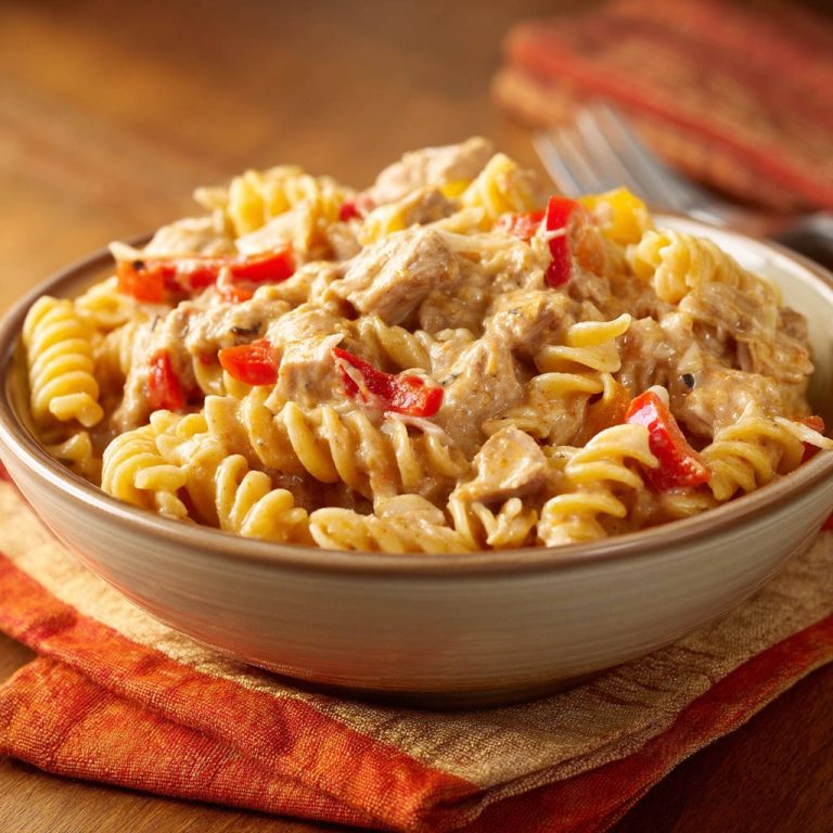 Cremige Hähnchen-Pasta mit Paprika als Nahaufnahme in einer Schüssel, serviert auf einem orangen Tuch.