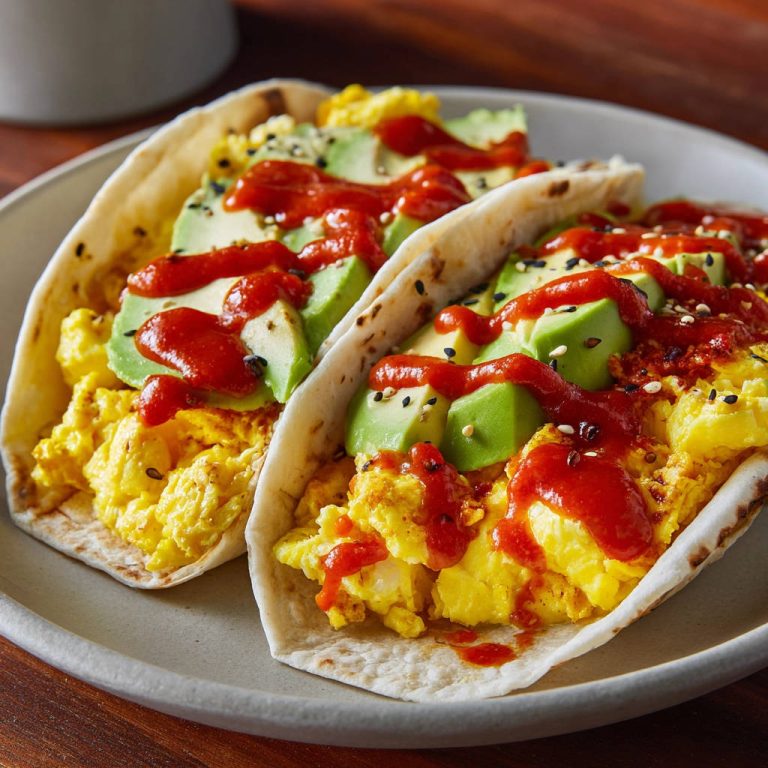 Frühstücks-Tacos mit Rührei und Avocado, nah aufgenommen mit einer roten Soße und Sesam.