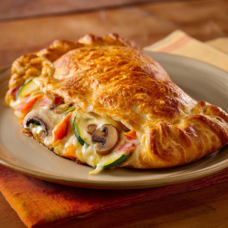 Gemüse-Calzone angeschnitten auf einem Teller, mit sichtbarer Füllung aus Zucchini, Pilzen und Karotten.