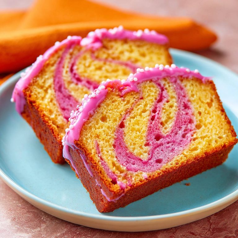 Marmorkuchen mit rosa Swirl, angeschnitten auf einem blauen Teller mit süßen Streuseln und rosa Glasur.