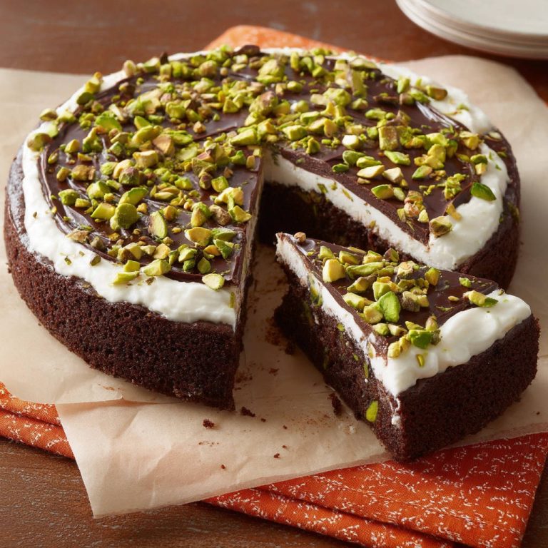 Schokoladenkuchen mit Frischkäsecreme und Pistazien, angeschnitten, zeigt saftigen Kuchenboden und cremige Füllung.