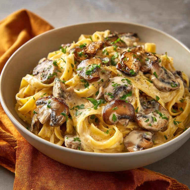 Tagliatelle mit cremiger Pilzrahmsoße, nah aufgenommen und in einer Schüssel serviert, mit frischer Petersilie garniert.
