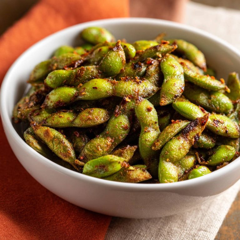 Würzige Edamame aus der Pfanne als Nahaufnahme in einer Schüssel, mit Gewürzen bestreut.