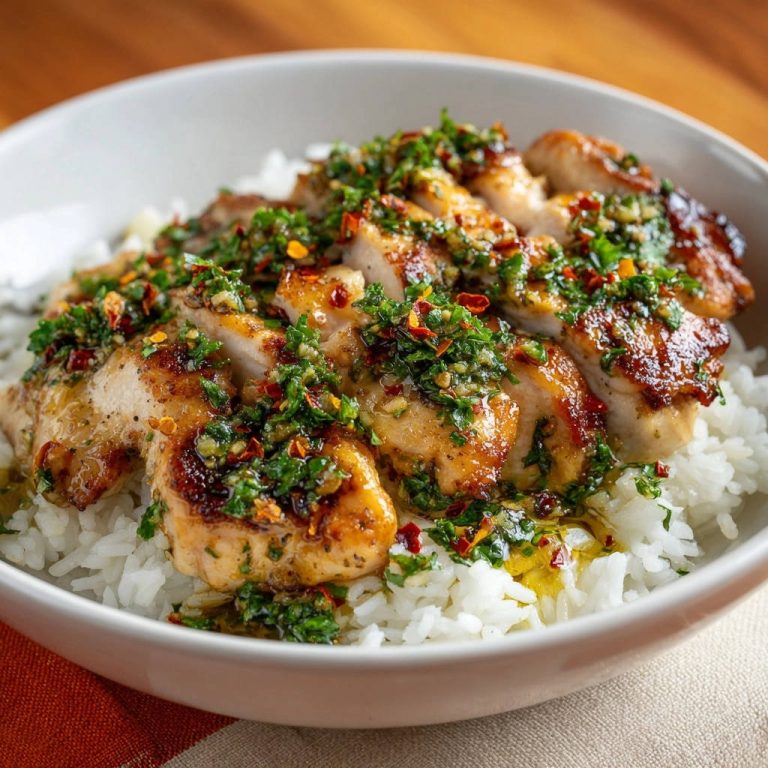 Saftiges Hähnchen mit Kräutersauce und Reis, nahaufnahme der geschnittenen Hähnchenbrust mit würziger Kräutersauce und roten Chiliflocken.