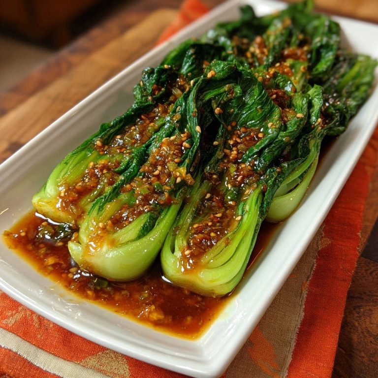 Asiatischer Bok Choy mit Knoblauch-Sesam-Soße, detailnah mit glänzender Sauce und Sesamkörnern auf den Gemüsestielen.