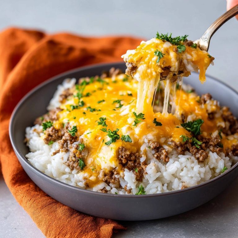Würzige Hackfleisch-Reis-Bowl mit geschmolzenem Käse, der von einer Gabel gezogen wird, garniert mit Petersilie.