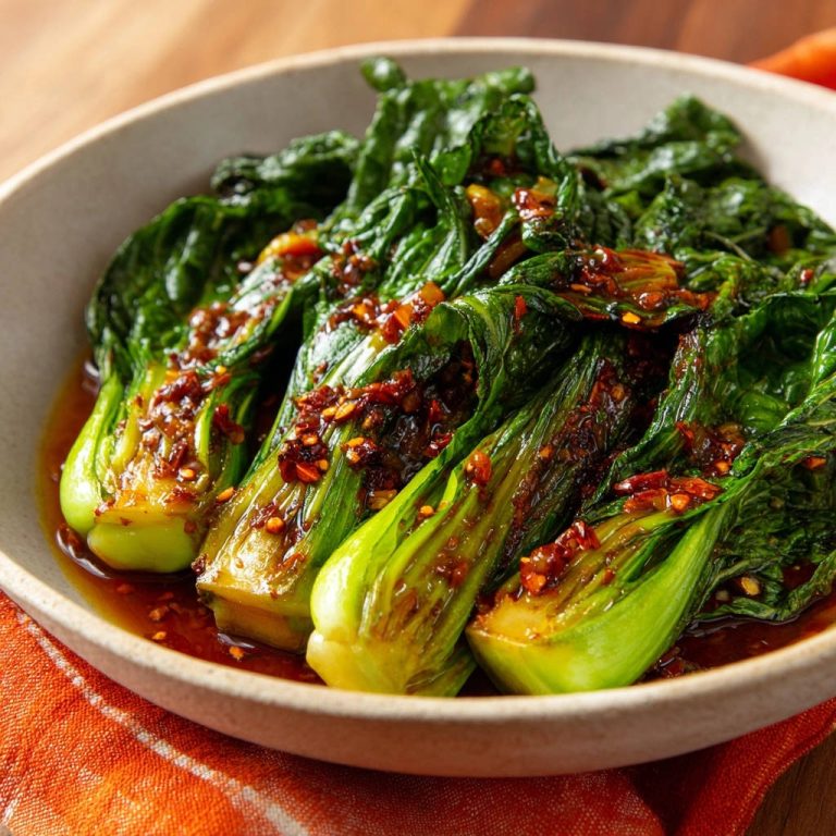 Würziger Pak Choi aus dem Wok, detailreiche Nahaufnahme der glasierten Blätter und Stiele mit Chili-Flocken.