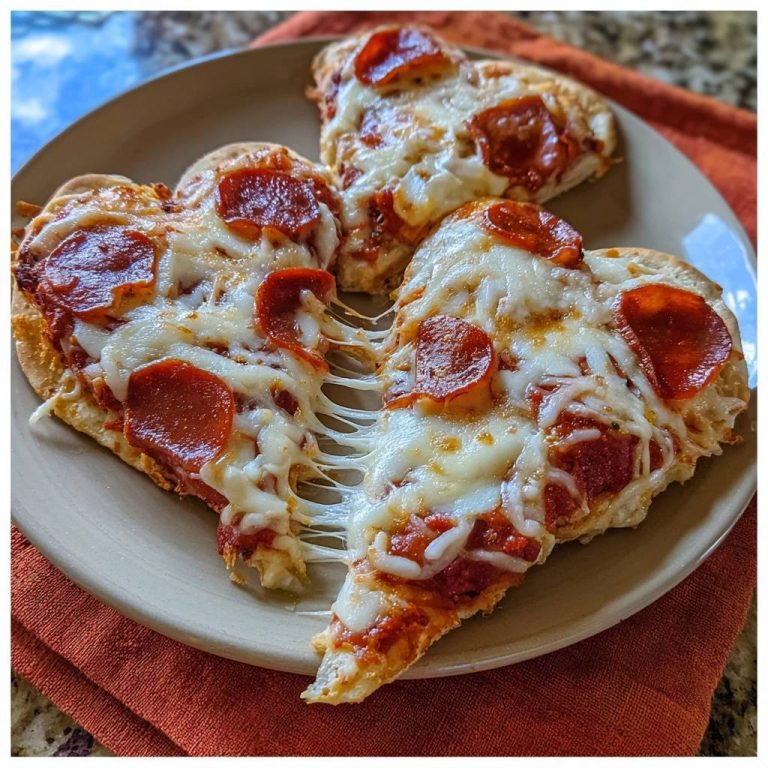 Herzförmige Pepperoni-Pizza mit geschmolzenem Käse, der zwischen zwei Stücken der Pizza herausgezogen wird.