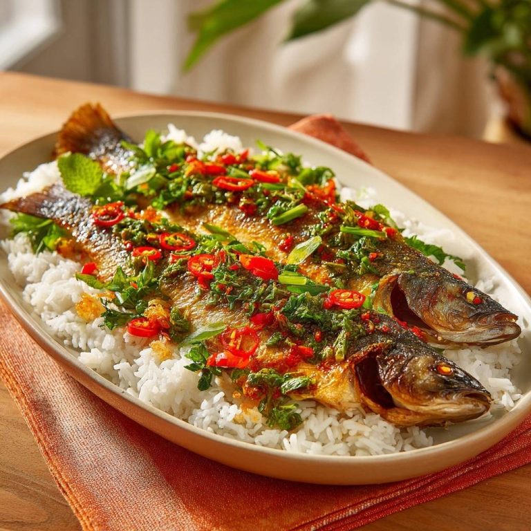 Knusprige Forelle mit Chili-Kräutern auf Reis, im Detail mit frischer Garnitur und roten Chilischeiben.