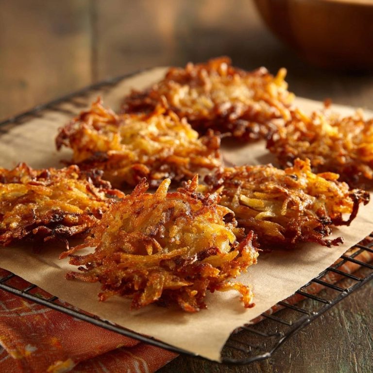 Knusprige Kartoffelpuffer, frisch gebacken und auf einem Rost zum Abkühlen ausgelegt, mit sichtbarer Textur.