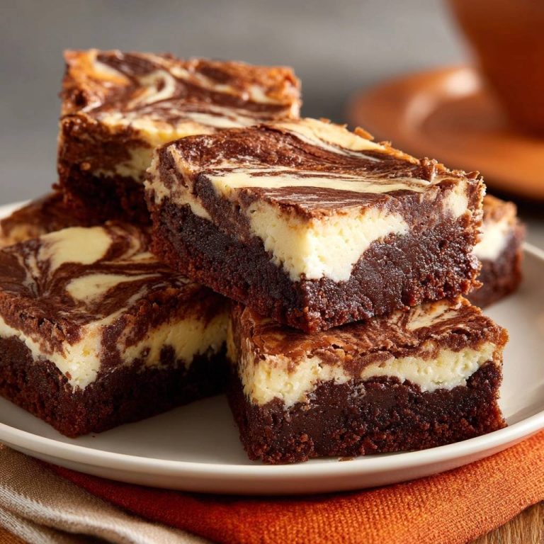 Marmorierte Schoko-Cheesecake-Brownies angeschnitten auf einem Teller, mit cremiger Käsekuchenschicht und dunklem Schokoladenboden.