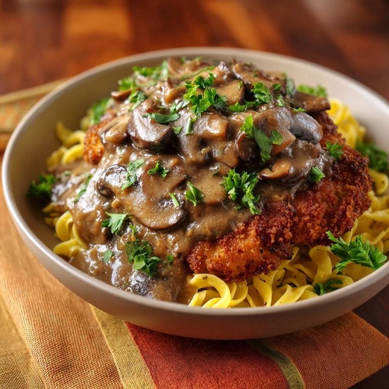 Paniertes Hähnchenschnitzel mit Pilz-Rahm-Soße und Bandnudeln, serviert in einer Schüssel mit Nahaufnahme der Pilz-Rahm-Soße und Petersilie.