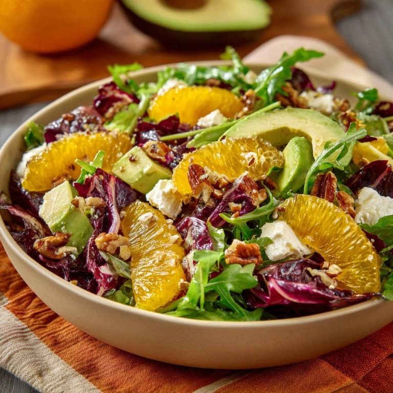 Radicchio-Orangen-Avocado-Salat nahaufnahme mit Orangenstücken, Avocado und Nüssen in einer Schüssel auf einem gestreiften Tuch.