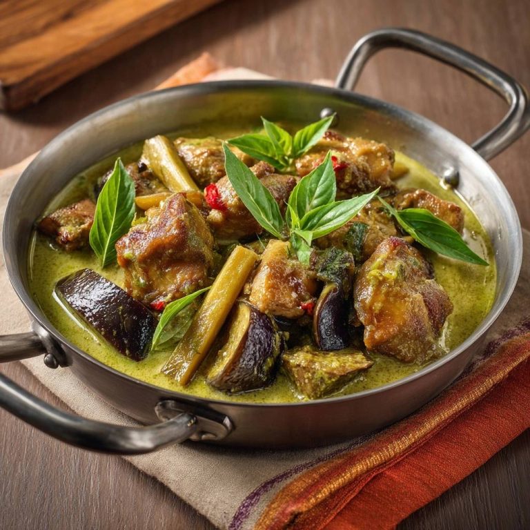 Thai Grünes Curry mit Aubergine und Rind, eine Nahaufnahme des Gerichts in einer Servierschale, garniert mit frischem Basilikum.