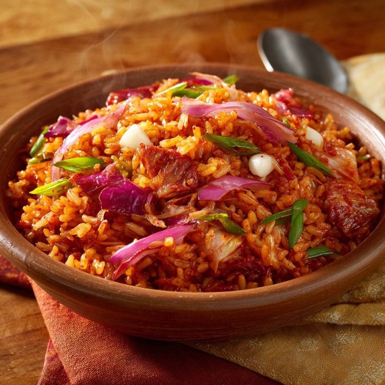 Kimchi Bokkeumbap in einer heissen Tonschüssel, dampfend und mit roten Zwiebeln garniert