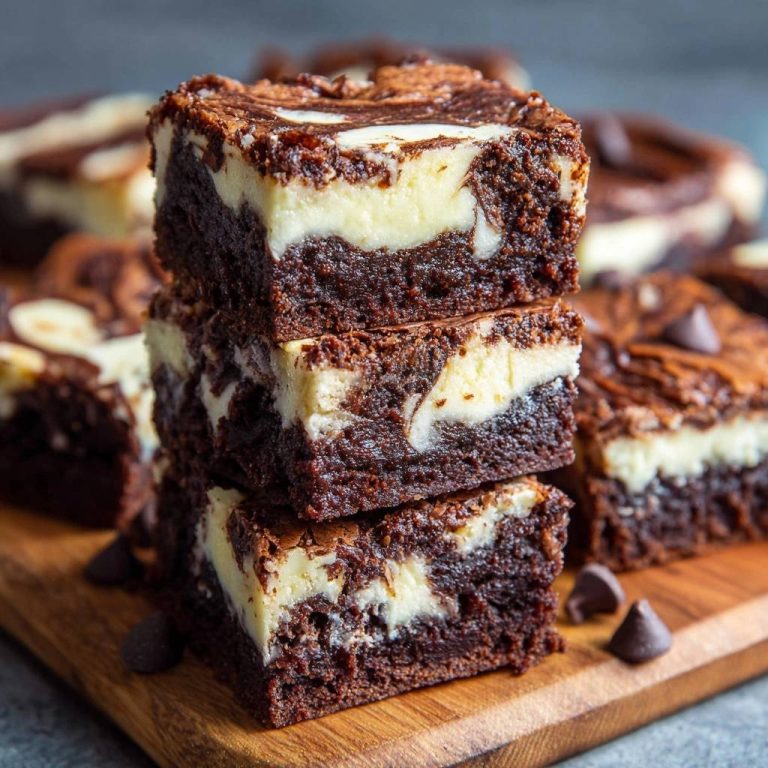 Marmor-Cheesecake-Brownies als Nahaufnahme gestapelt auf einem Holzbrett mit Schokoladenstückchen.