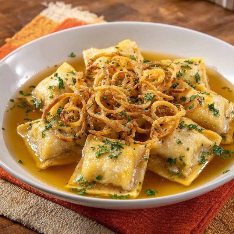 Ravioli in goldener Brühe mit knusprigen Zwiebeln, garniert mit frischer Petersilie, in einer weißen Schüssel serviert.
