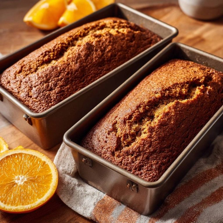 Saftiger Karotten-Orangen-Kuchen frisch aus zwei rechteckigen Backformen auf einem Holztisch