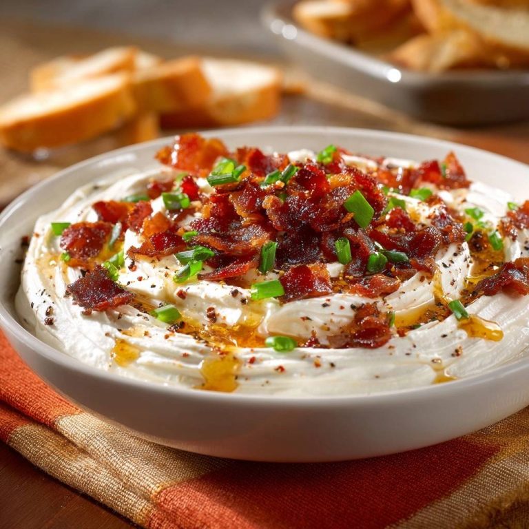 Knuspriger Bacon-Honig-Dip garniert mit Speck und Schnittlauch, serviert in einer Schüssel mit Brot im Hintergrund.