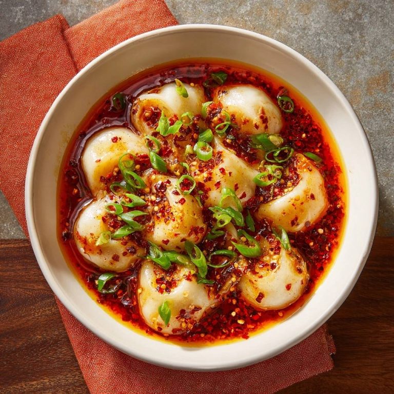 Scharfe Chiliöl-Dumplings saftig & platzenfrei in scharfer Chiliöl-Sauce mit Frühlingszwiebelgarnitur, von oben gesehen.