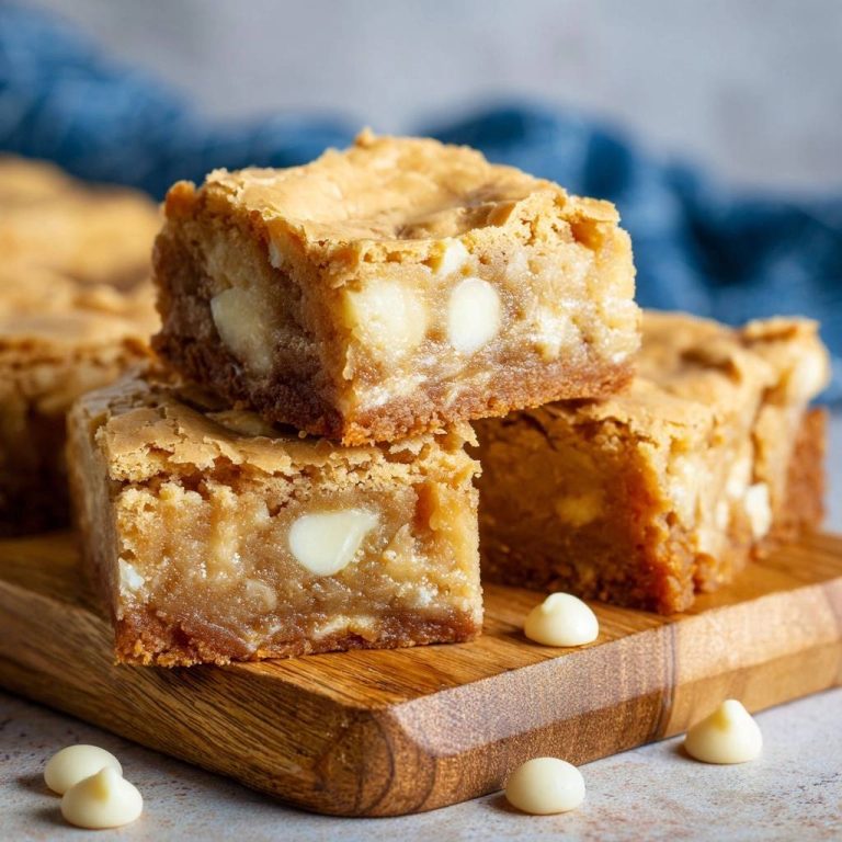 White Chocolate Blondies – Nie wieder trocken! Gestapelte blondies in Nahaufnahme mit weißen Schokoladenstückchen.