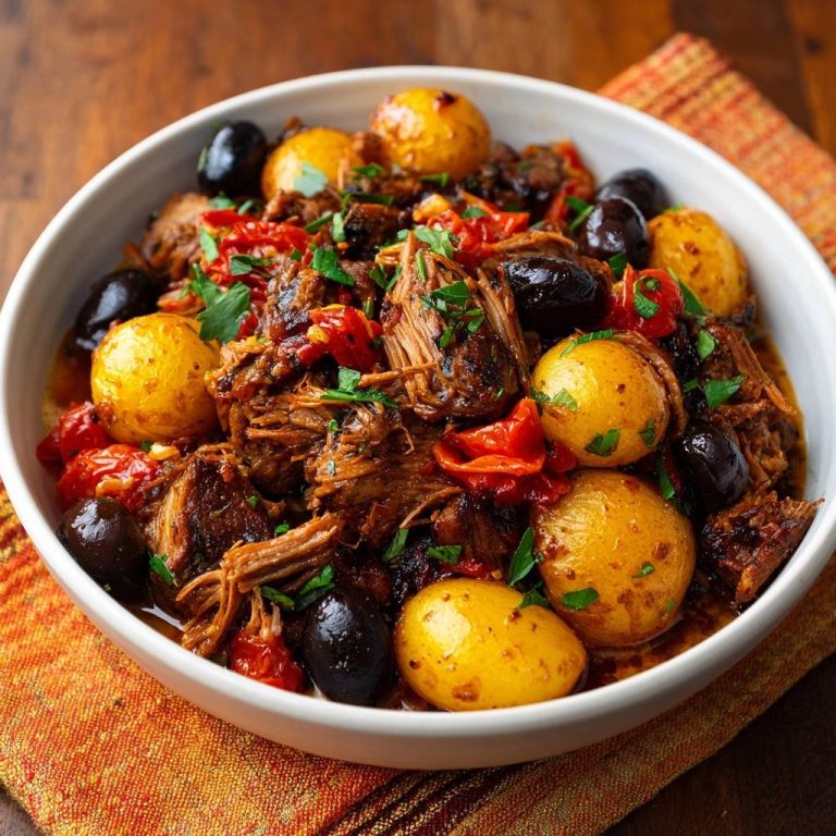 Zartes Pulled Rind mit Kartoffeln, Oliven und Paprika in einer Schüssel, Nahaufnahme mit frischer Petersilie garniert.