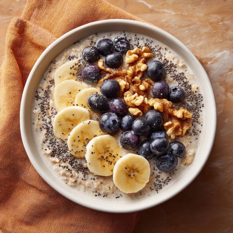 Cremiger Blaubeer-Bananen-Haferbrei, garniert mit Blaubeeren, Bananenscheiben und Walnüssen in einer Schüssel.