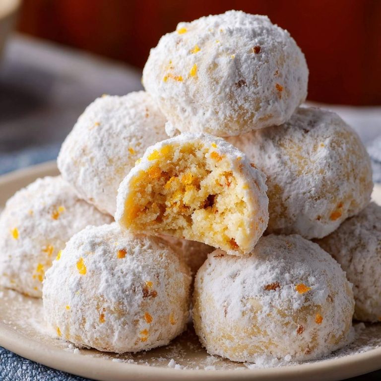 Orangen-Schneebälle mit Puderzucker und Orangenzesten, ein Ball ist angeschnitten und zeigt die saftige Textur innen.
