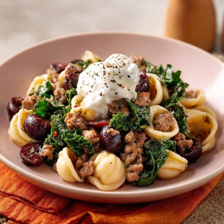 Orecchiette mit Rinderhack, Sauerkirschen, Grünkohl und Ricotta, serviert auf einem Teller mit einer Nahaufnahme der cremigen Ricotta-Topping.
