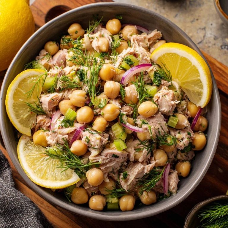Frischer Thunfisch-Kichererbsen-Salat mit Dill, garniert mit Zitronenspalten und frischem Dill, in einer Schüssel serviert.