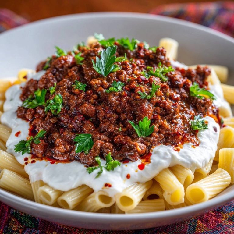 Türkische Kıymalı Rigatoni mit Joghurt, detailreiche Nahaufnahme des saftigen Hackfleischs und der cremigen Joghurtsoße, garniert mit Petersilie.