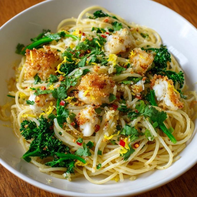 Zitronen-Knoblauch-Pasta mit knusprigem Fisch, Nahaufnahme der Pasta mit Fischstücken und Kräutern garniert